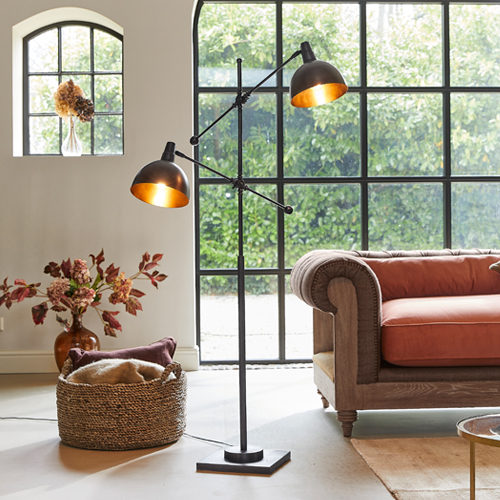 Lampadaire noir en métal avec deux abat-jours réglables dans un salon moderne avec canapé orange