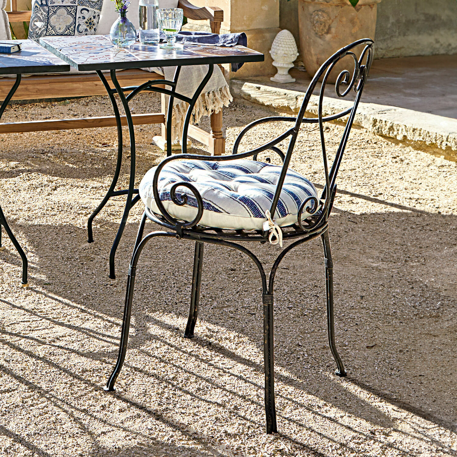 Chaise Aube Chaise de jardin en métal noir avec coussin rayé bleu et blanc sur terrasse ensoleillée