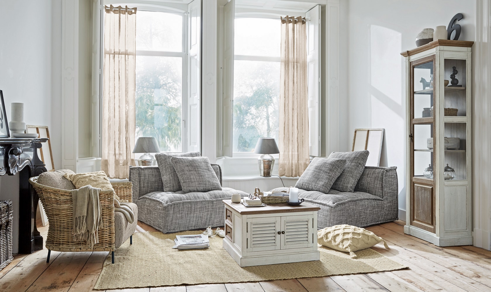 Lichte woonkamer met grijze fauteuils en witte houten kast op jute vloerkleed, Scandinavische stijl