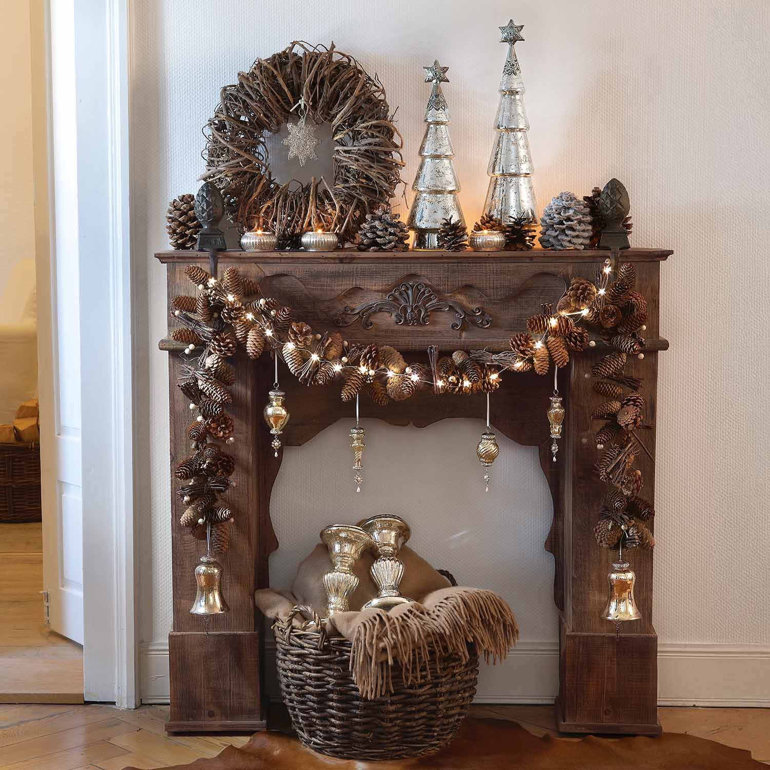 Rustieke houten open haard versierd met dennenappels, lichtjes en zilveren kerstdecoraties