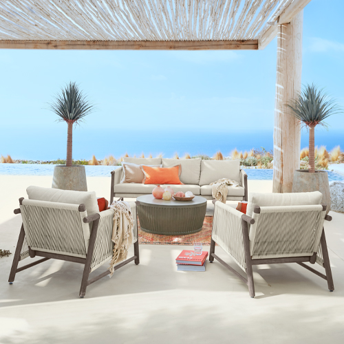 Buitenmeubelset met beige kussens en houten frame op terras met zeezicht onder pergola