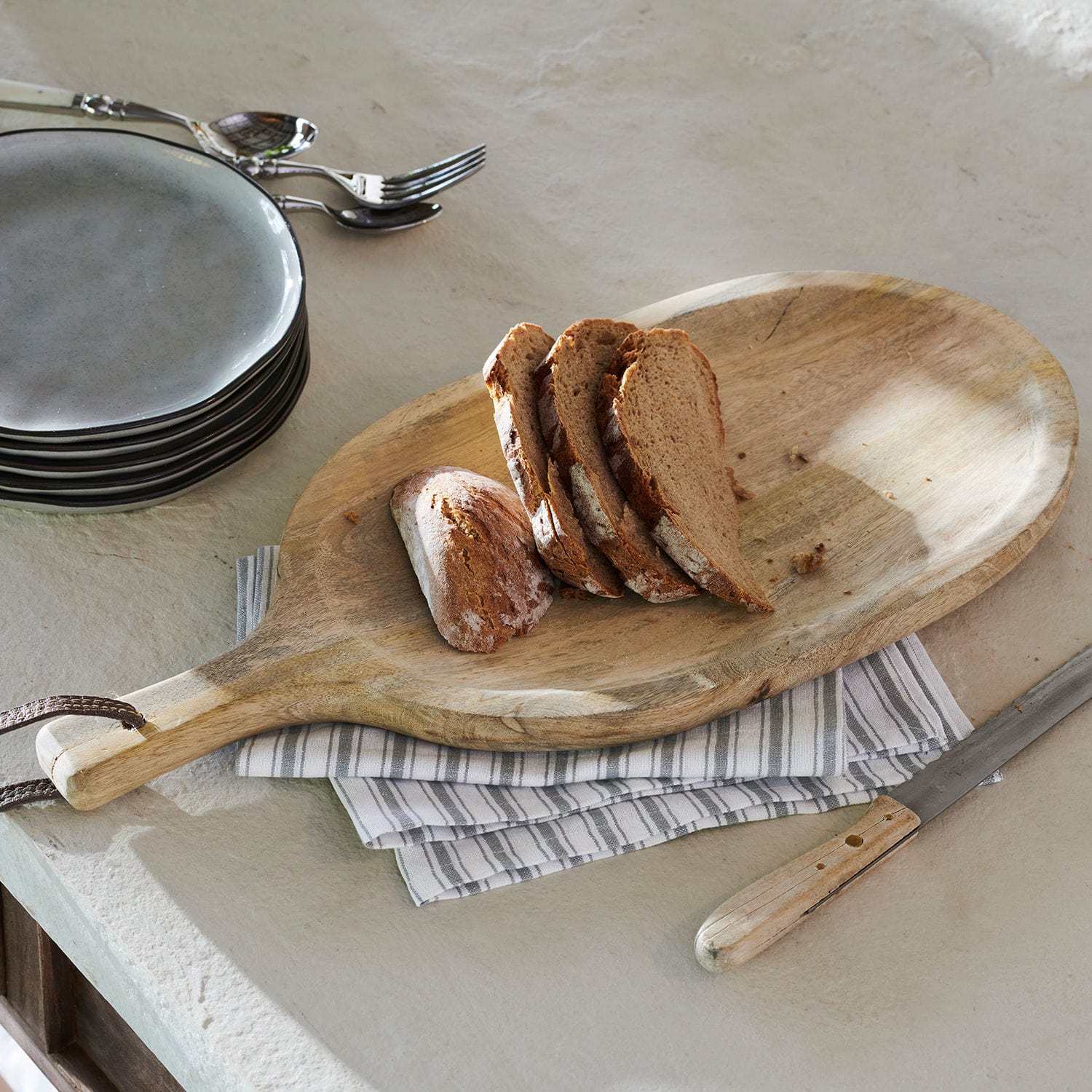Borrelplank Journée Houten snijplank met handvat en sneetjes brood op een lichtgrijze keukenblad