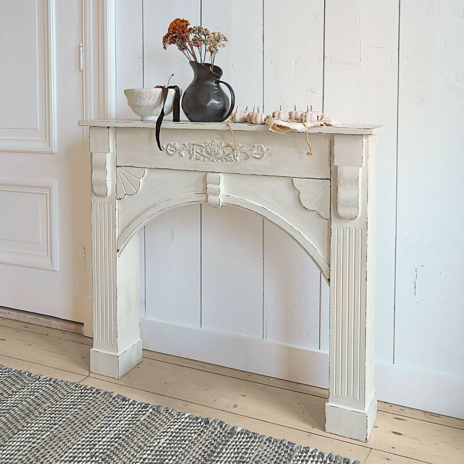 Haardschouw Maxwell Witte houten sidetable met decoratieve houtsnijwerk en vaas met gedroogde bloemen erop