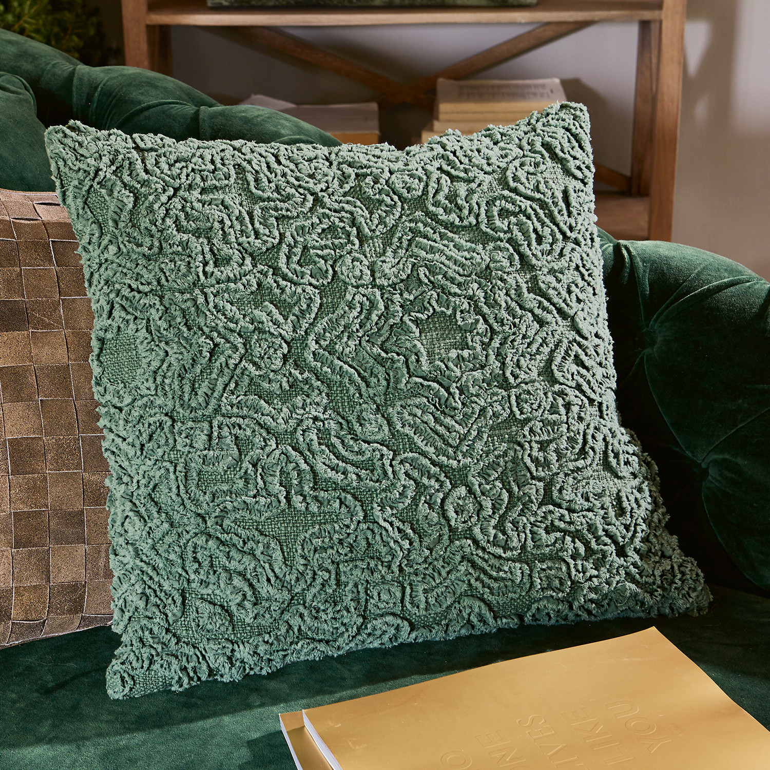 Coussin décoratif vert en tissu doux sur un canapé vert, accessoire d'intérieur tendance