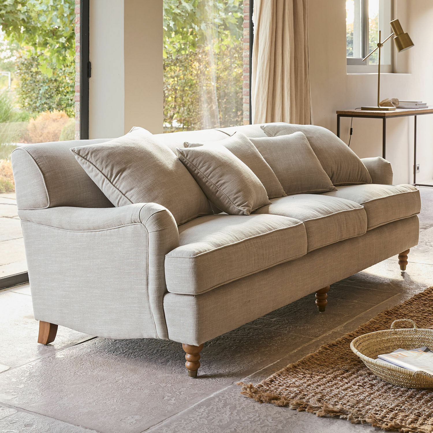 Bank Isa Beige gestoffeerde bank met kussens en houten poten in lichte woonkamer met vloerkleed