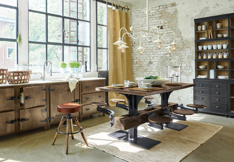 Table à manger industrielle en bois et métal avec tabourets intégrés dans une cuisine lumineuse avec grande fenêtre