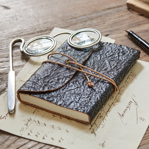 Carnet noir en cuir texturé avec lien en corde sur table en bois avec lunettes et stylo plume