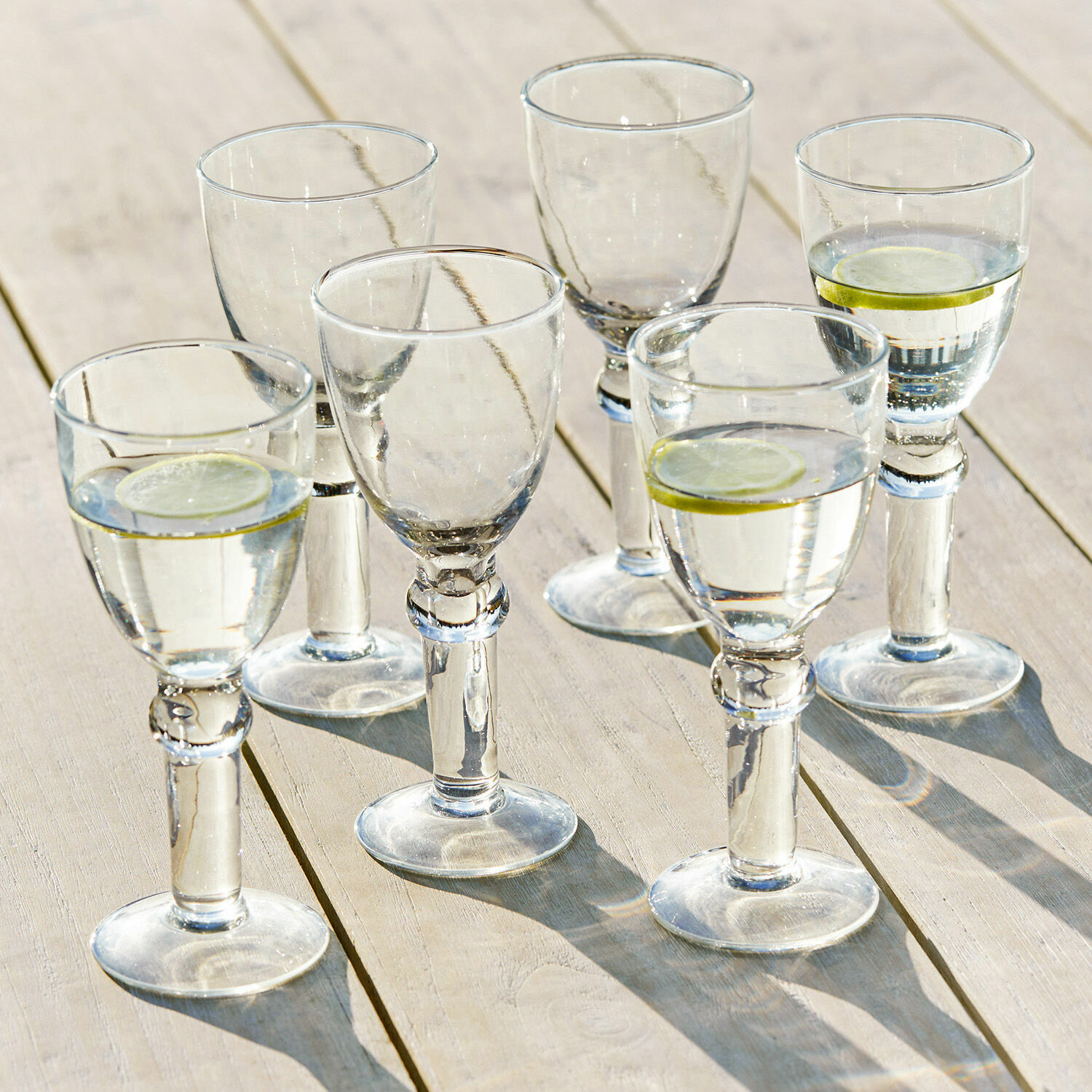 Wijnglas set van 6 Devon Set van zes heldere glazen met water en schijfjes citroen op lichte houten tafel