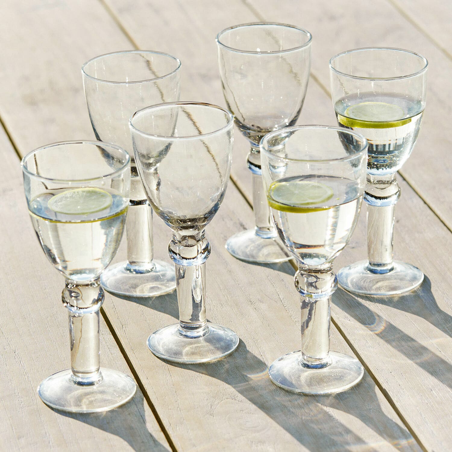 Lot de 6 verres à vin Devon Ensemble de six verres transparents avec eau et tranches de citron sur table en bois clair