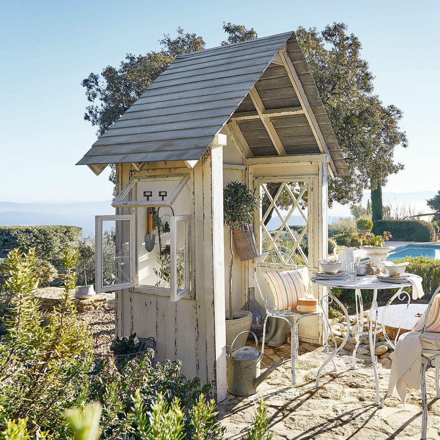 Maisonnette de jardin Sumter Kiosque de jardin en bois blanc avec table et chaises en métal sur sol en pierre près de la piscine