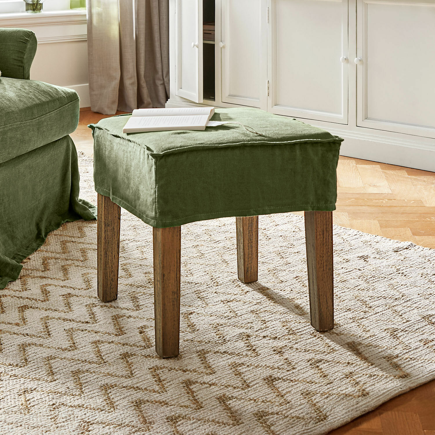 Kruk Vionnique Groene voetenbank met linnen bekleding en houten poten op lichte vloerkleed in woonkamer