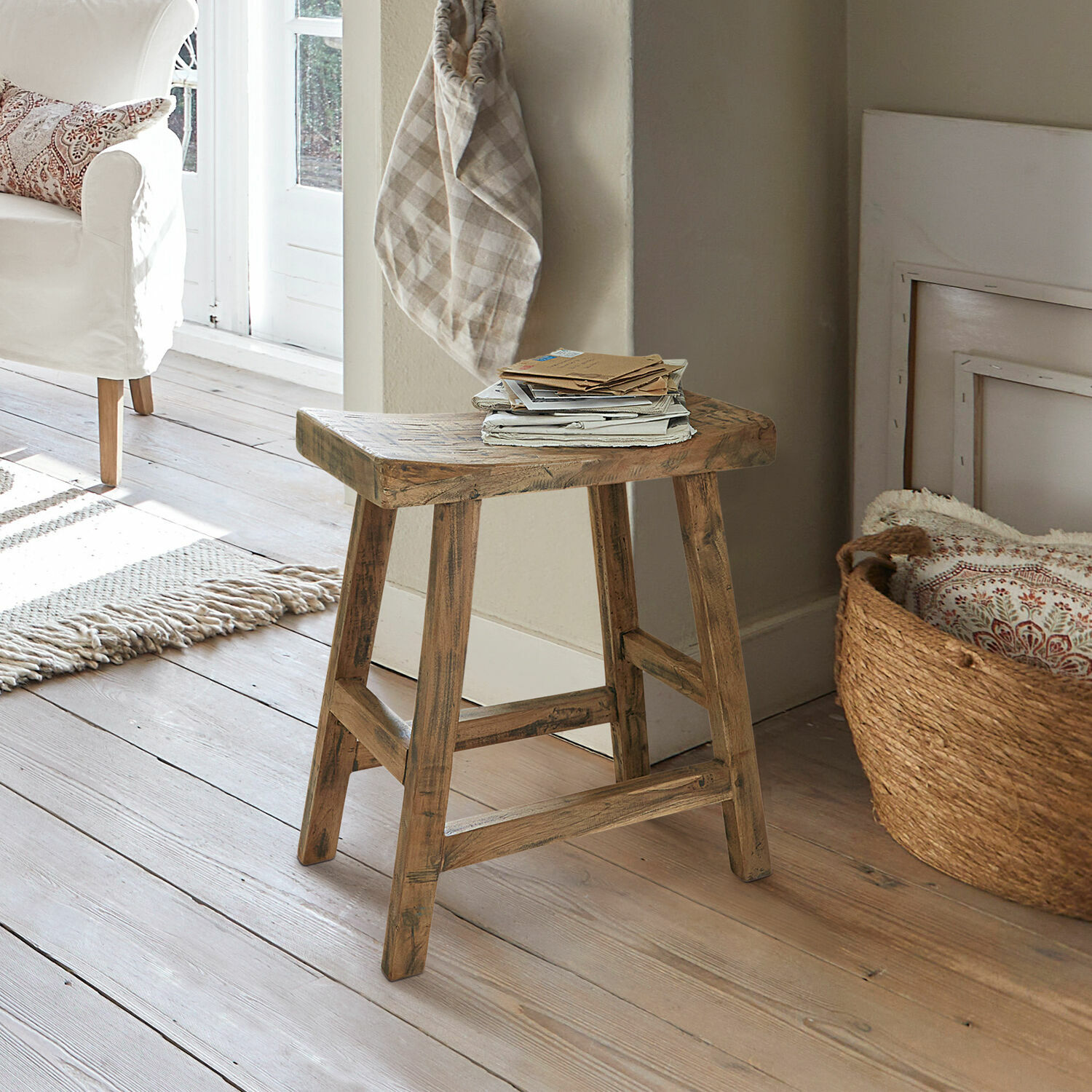 Tabouret Nael Tabouret en bois naturel posé sur un sol clair dans un salon lumineux et cosy