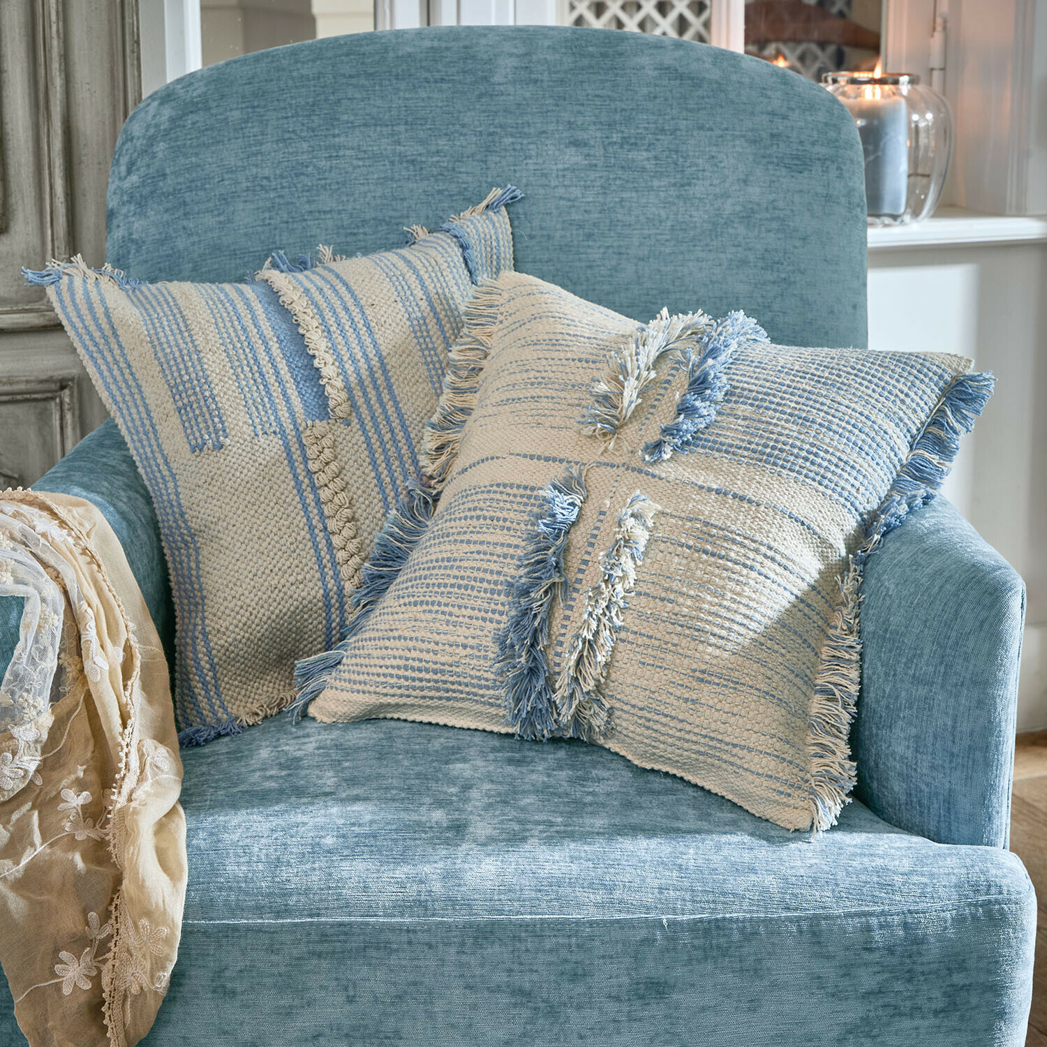 Lot de 2 housses de coussins Ciel d'Azur Deux coussins décoratifs en coton beige et bleu sur un fauteuil bleu doux dans un salon lumineux