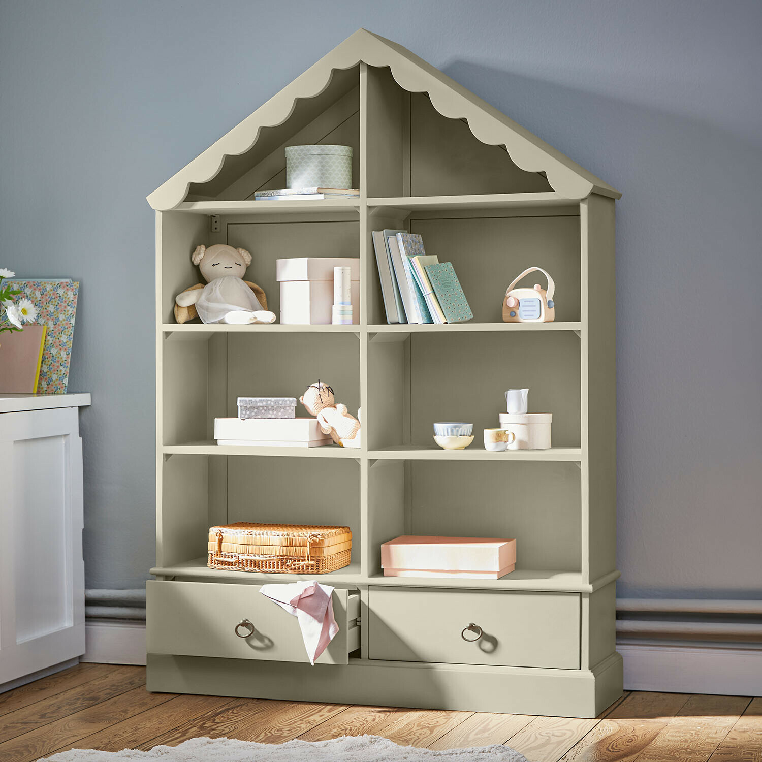 Étagère en forme de maison en bois vert olive avec jouets et boîtes de rangement dans une chambre d'enfant