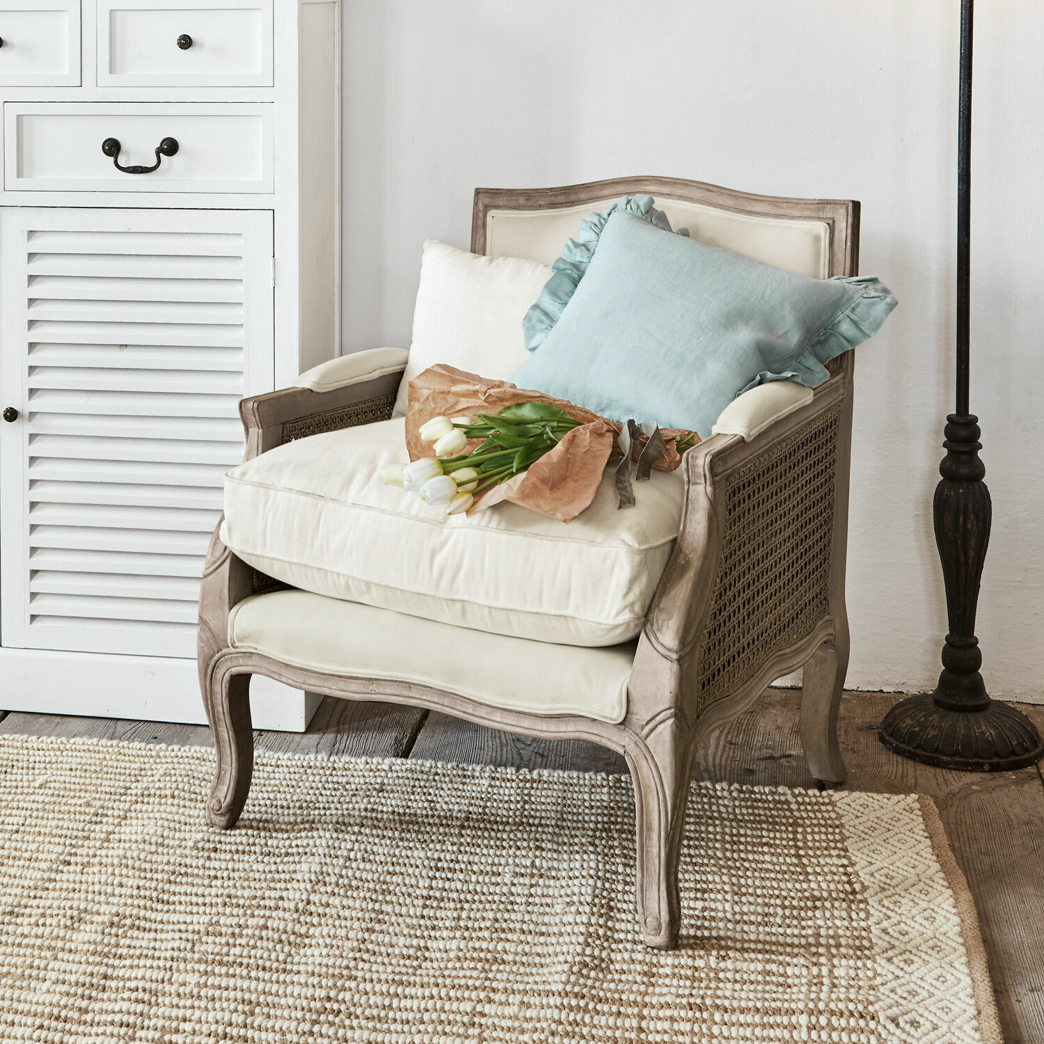 Fauteuil Alfort Klassieke stoel van hout en crèmekleurige stof met kussens en bos witte tulpen