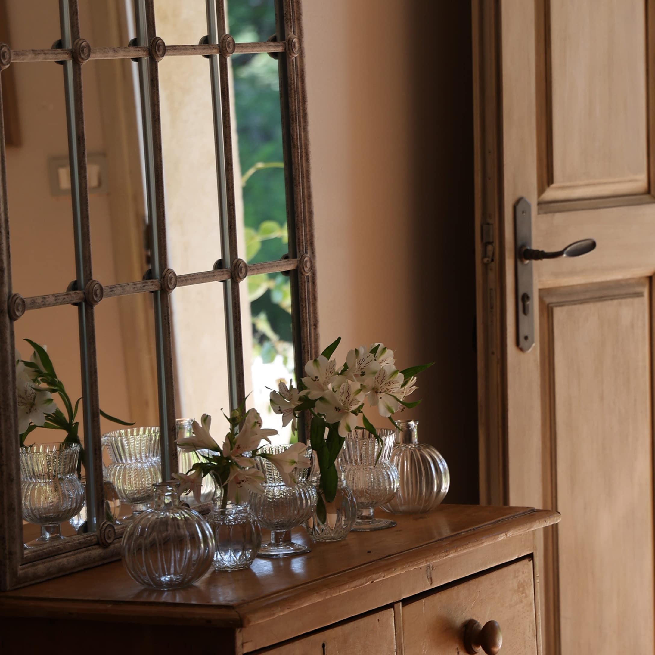 Vases en verre transparent avec fleurs blanches sur commode en bois dans un intérieur rustique