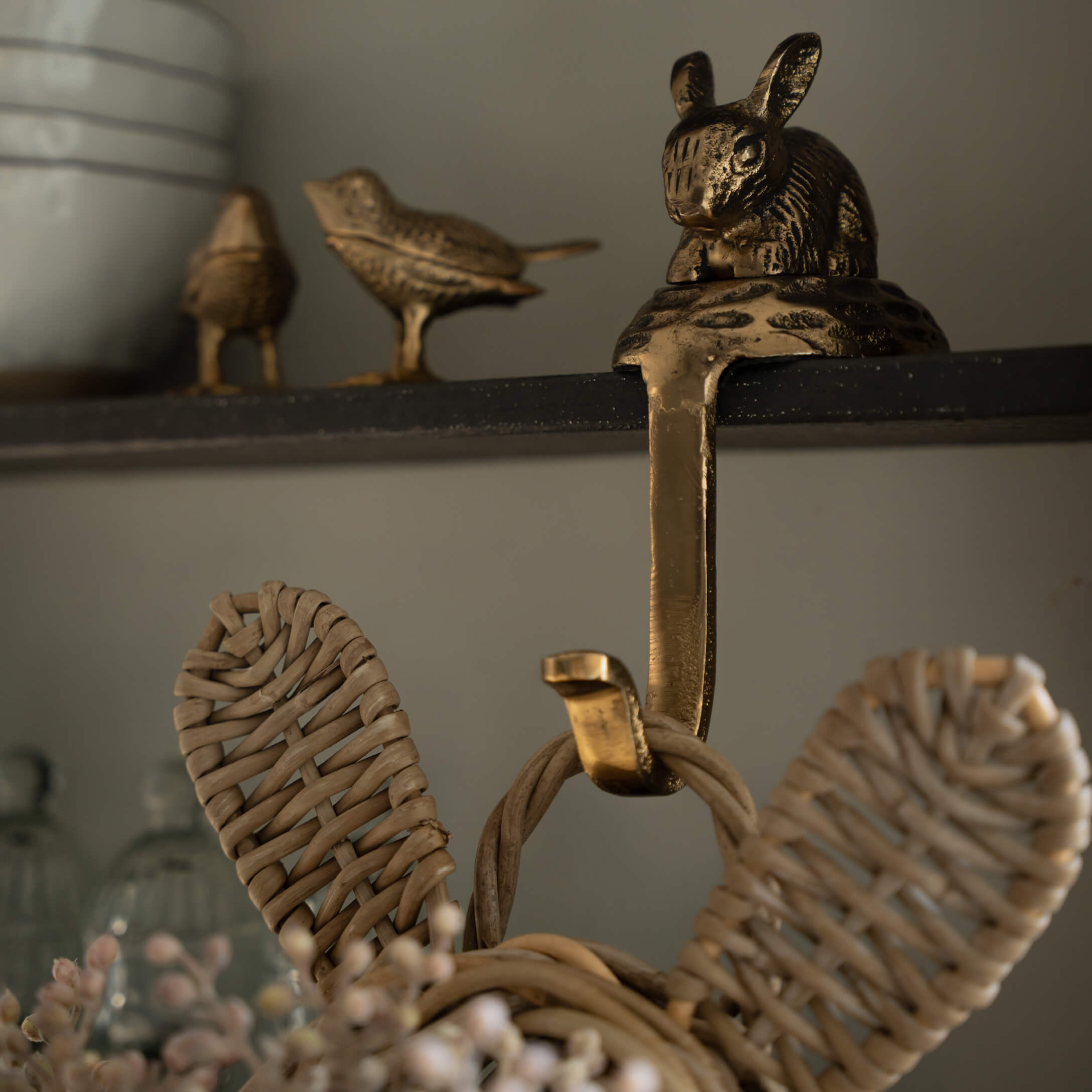 Gouden messing haak met konijn- en vogelmotief aan zwarte plank voor woondecoratie