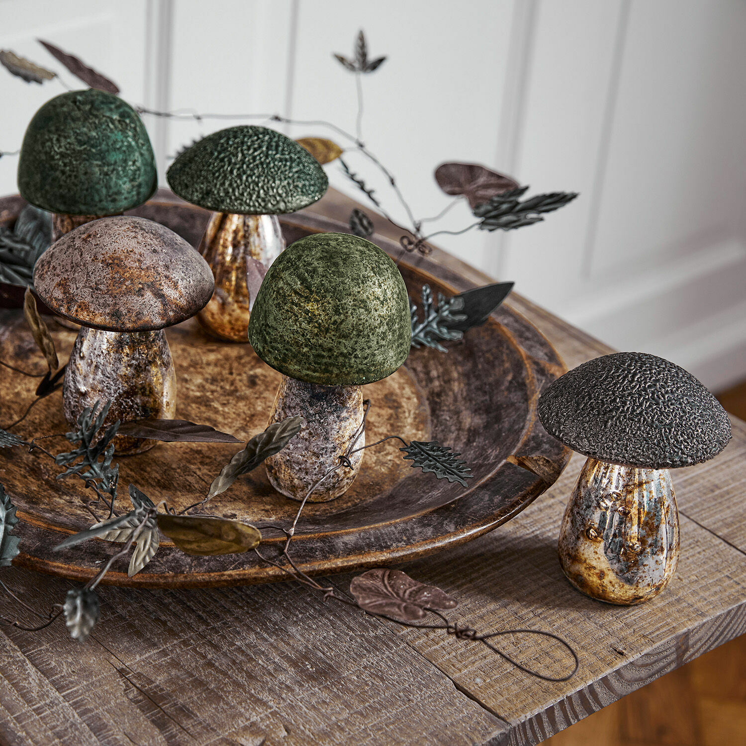 Lot de 5 champignons décoratifs Grana Champignons décoratifs en métal vert et marron sur une table en bois avec plateau rustique