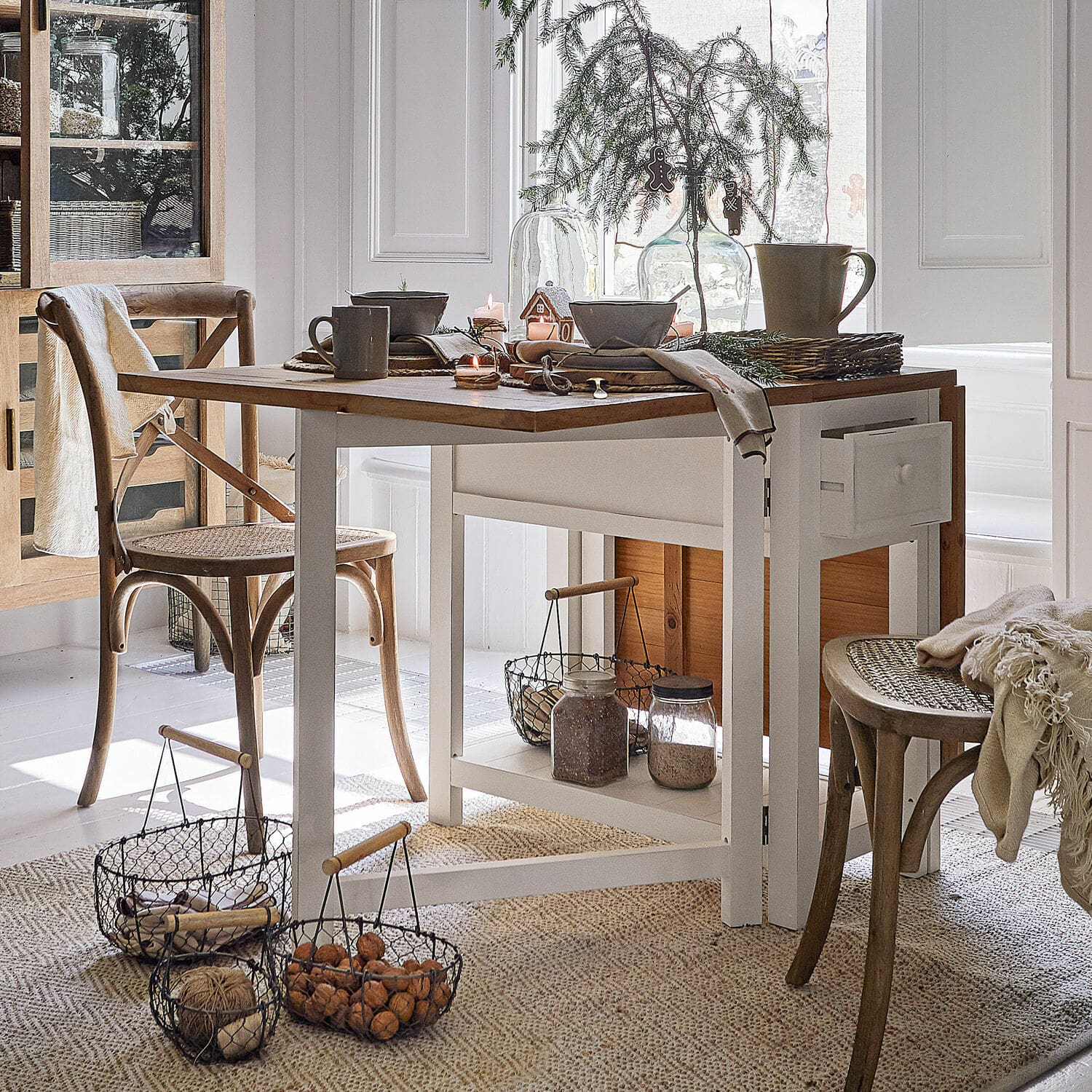 Tafel Dale Eetkamer met witte houten tafel en natuurlijke rieten stoelen, kerstdecoratie en manden met noten