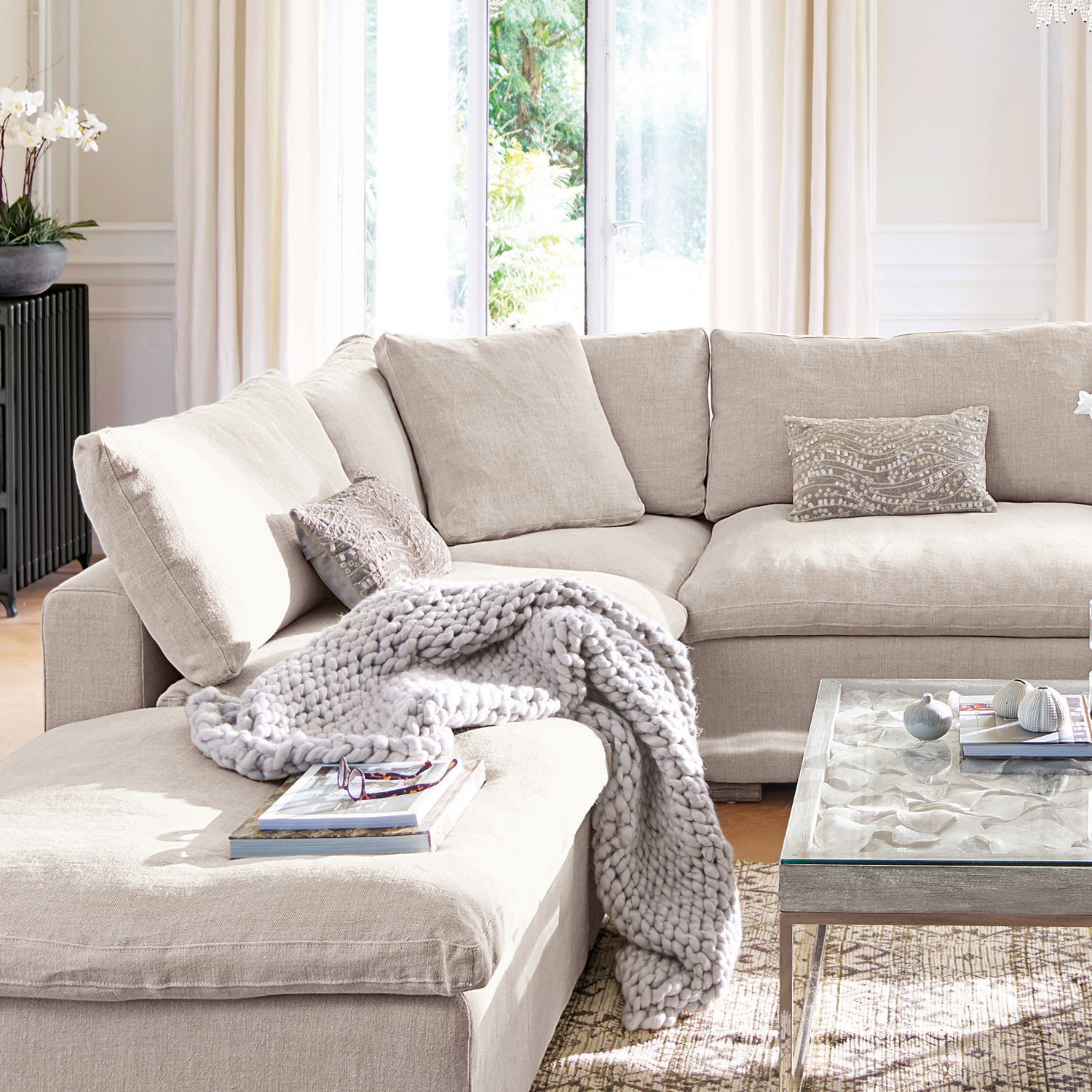 Fauteuil Bennington Corner Canapé d'angle beige en tissu avec coussins et plaid tricoté gris dans un salon lumineux