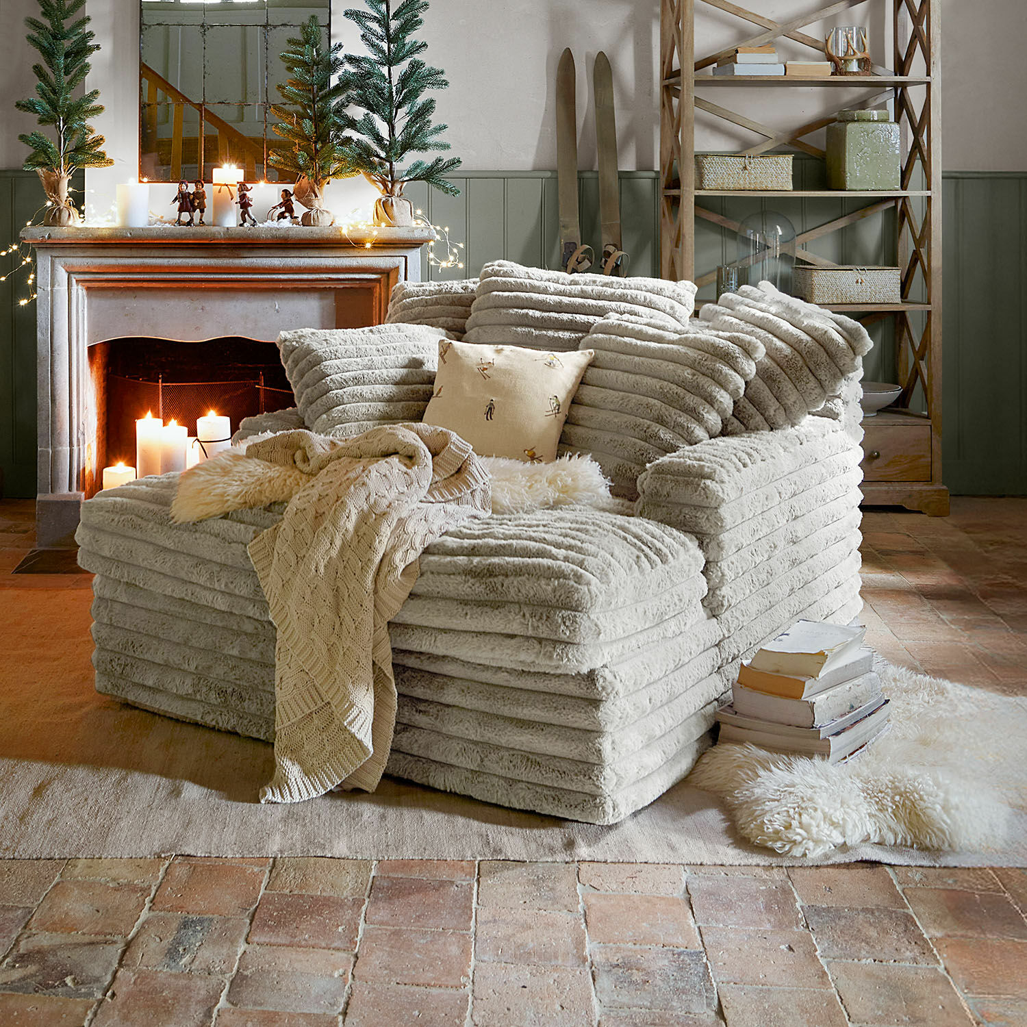 Chaise longue Woodminster Comfortabele fauteuil van zachte beige stof in rustieke woonkamer met open haard en kerstdecoratie