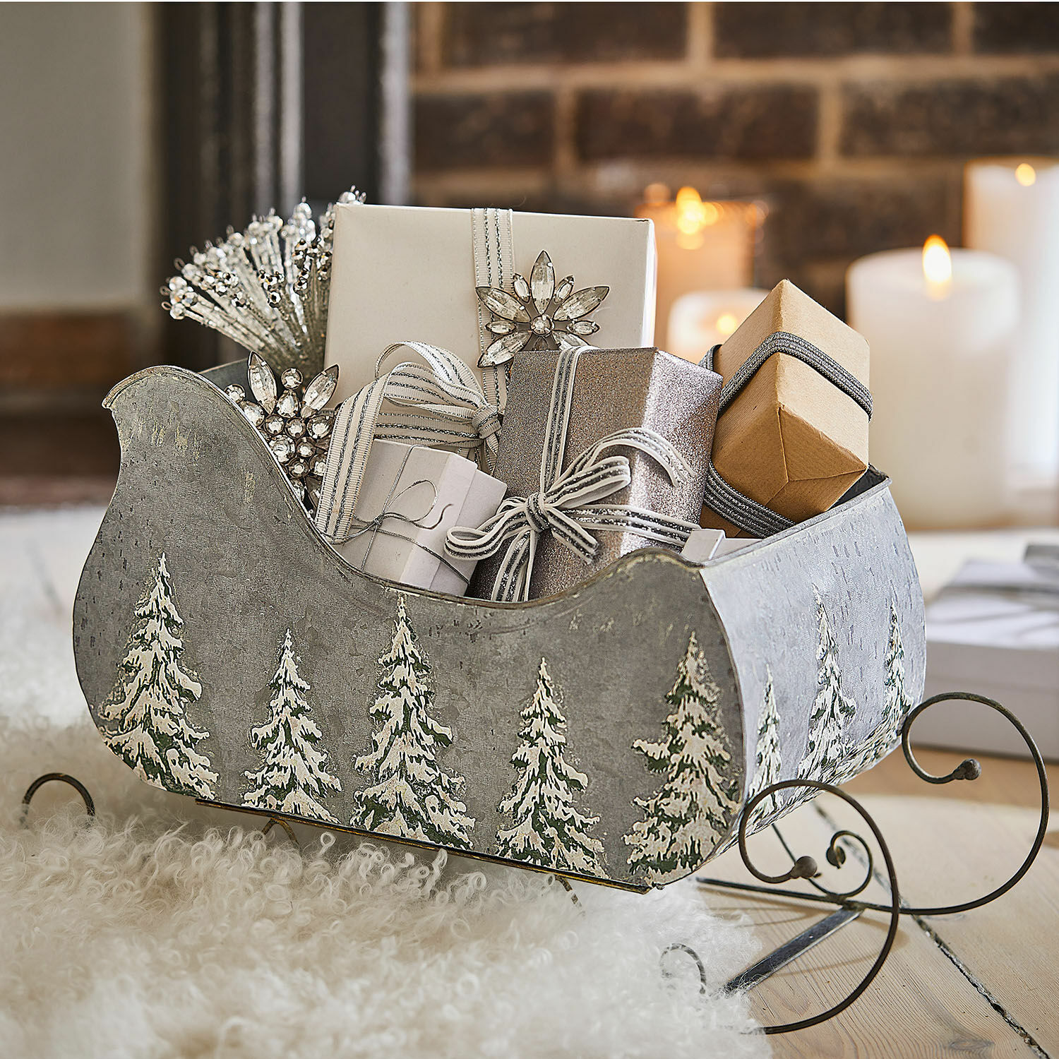 Grijze metalen slee met dennenboommotief, gevuld met cadeaus en kerstdecoraties