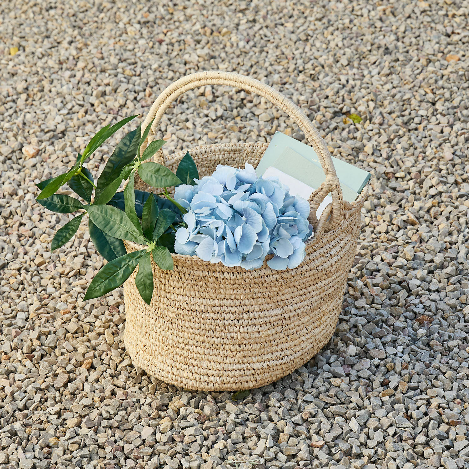 Mand Shanoura Natuurlijke gevlochten zeegrasmand met blauwe bloemen en groene bladeren op kiezelstenen