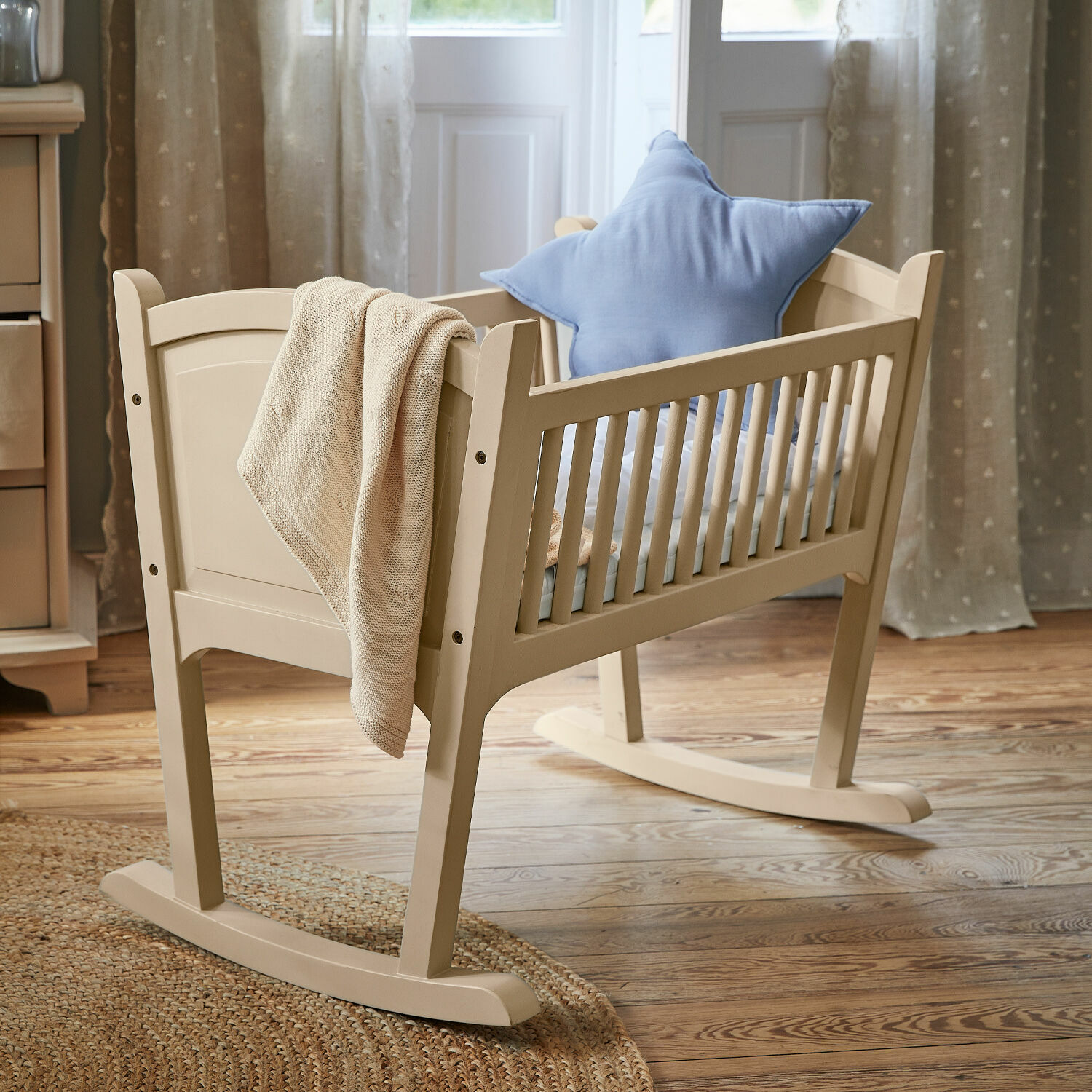 Wieg Aiguillon Beige houten wieg met blauwe stervormige kussen en gebreide deken in kamer