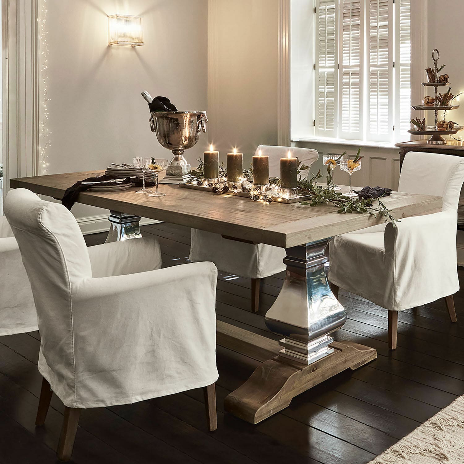Eettafel Filton Lichte houten eettafel met metalen poten en witte stoelhoezen in een elegante kamer