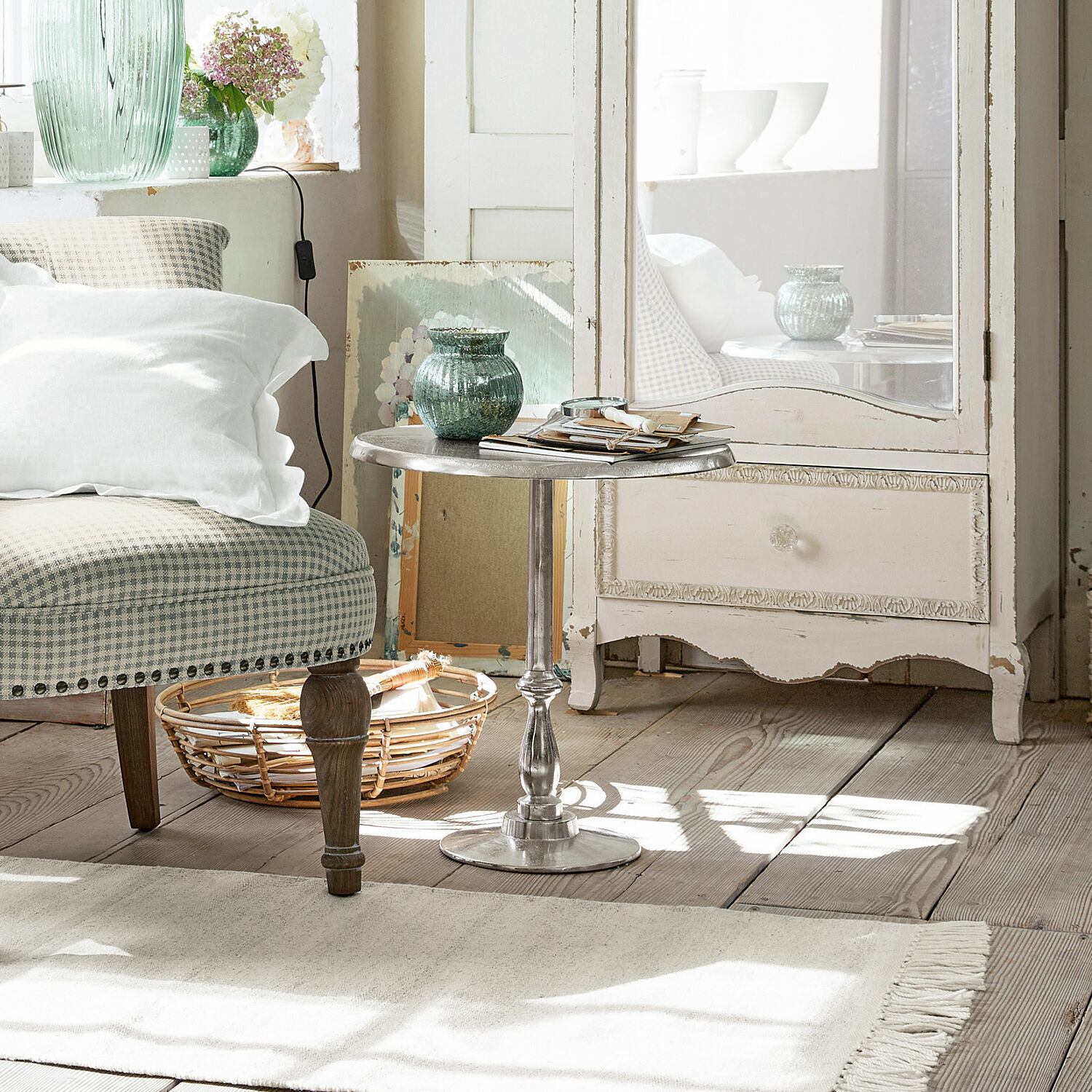 Bijzettafel Eppeville Ronde metalen bijzettafel in zilverkleur in lichte woonkamer met beige fauteuil en rieten mand