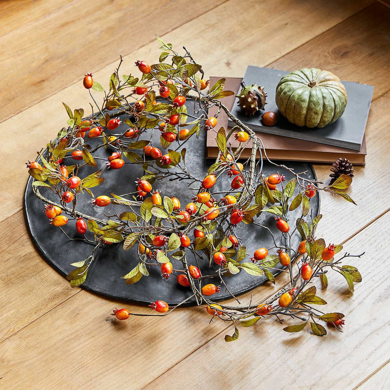 Guirlande Silovar Couronne décorative avec fruits rouges et orange sur plateau noir posé sur table en bois