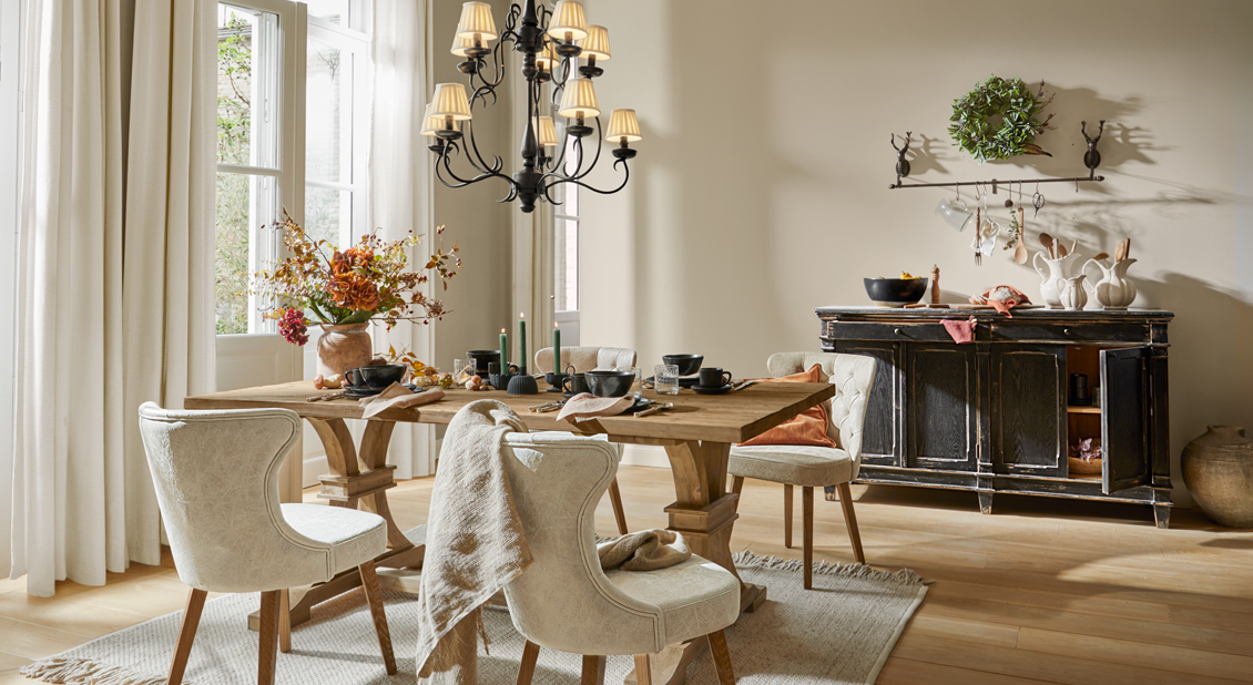 Salle à manger rustique avec table en bois, chaises rembourrées crème et buffet noir patiné