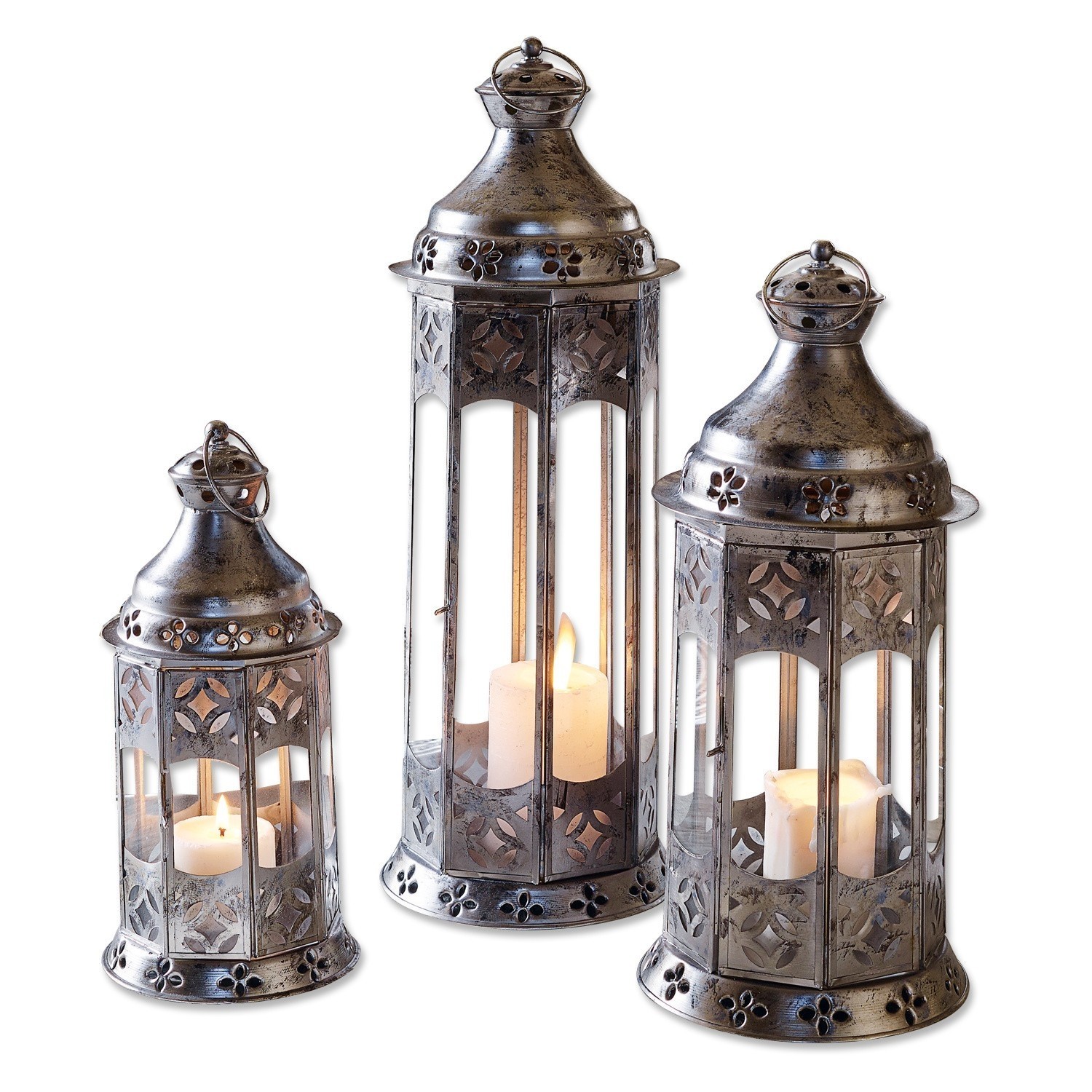 Ensemble de trois lanternes en métal argenté avec motifs décoratifs et bougies allumées à l'intérieur