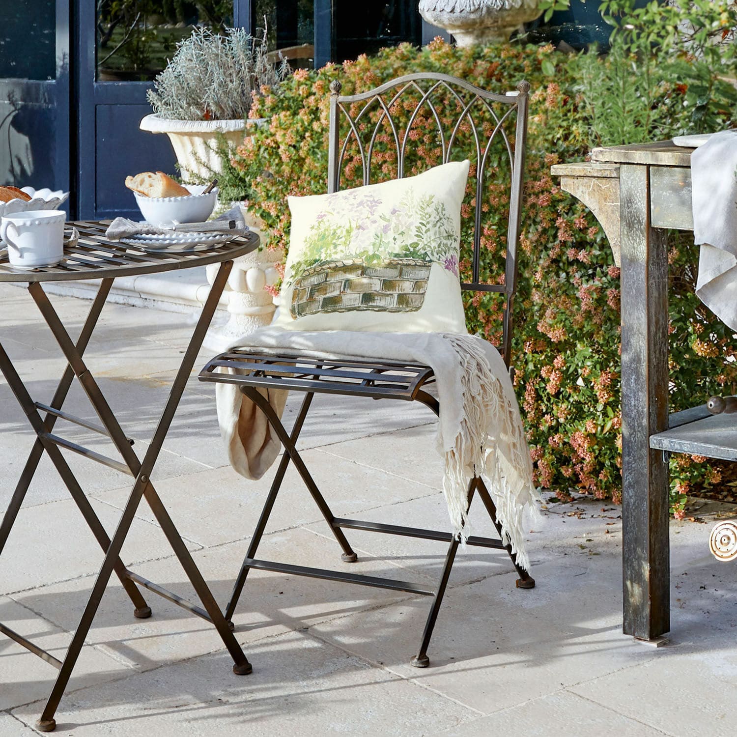 Chaise Brignoles Table et chaise pliantes en métal brun sur terrasse avec coussin décoratif et plaid