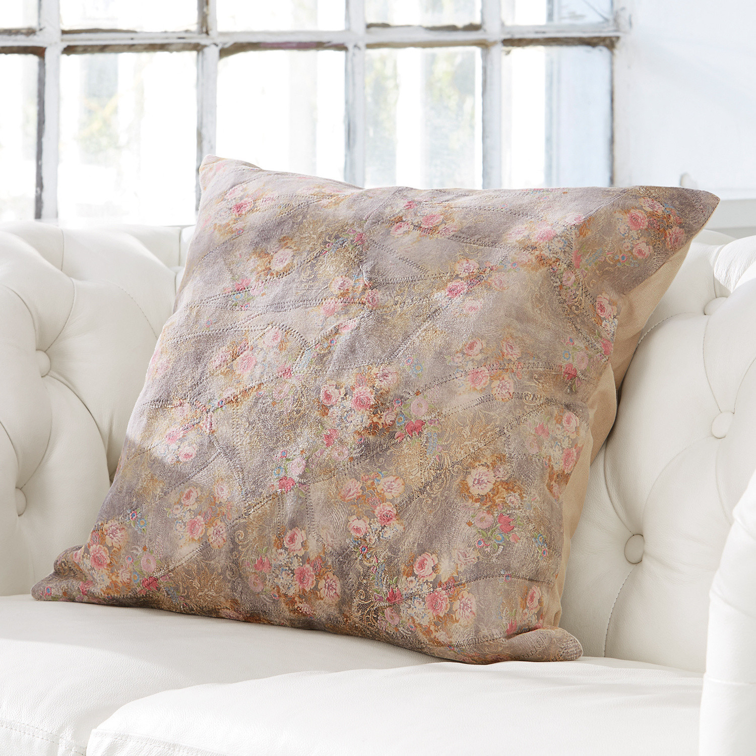 Coussin décoratif avec motif floral pastel sur fond clair posé sur un canapé blanc
