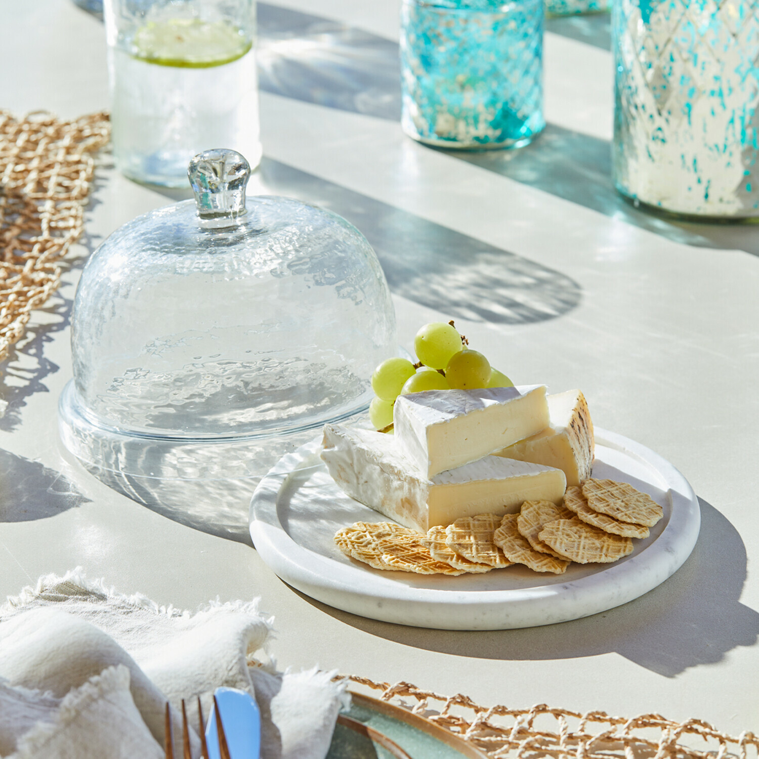 Cloche en verre avec plateau Barnsdale Cloche en verre transparent à côté d'une assiette avec fromage, crackers et raisins verts sur table lumineuse