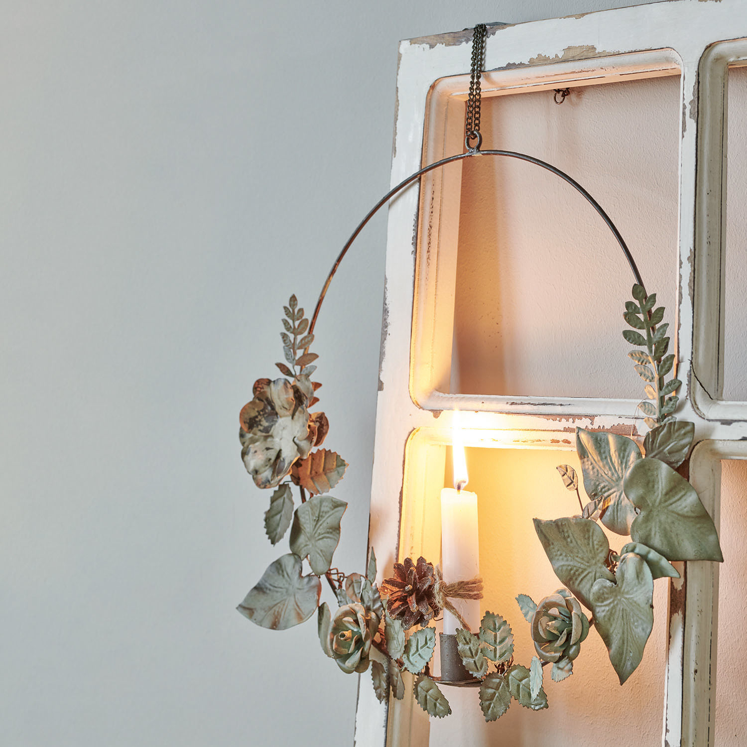 Kaarshouder Néville Metalen krans met groene bladeren en bloemen, witte decoratieve kaars brandt