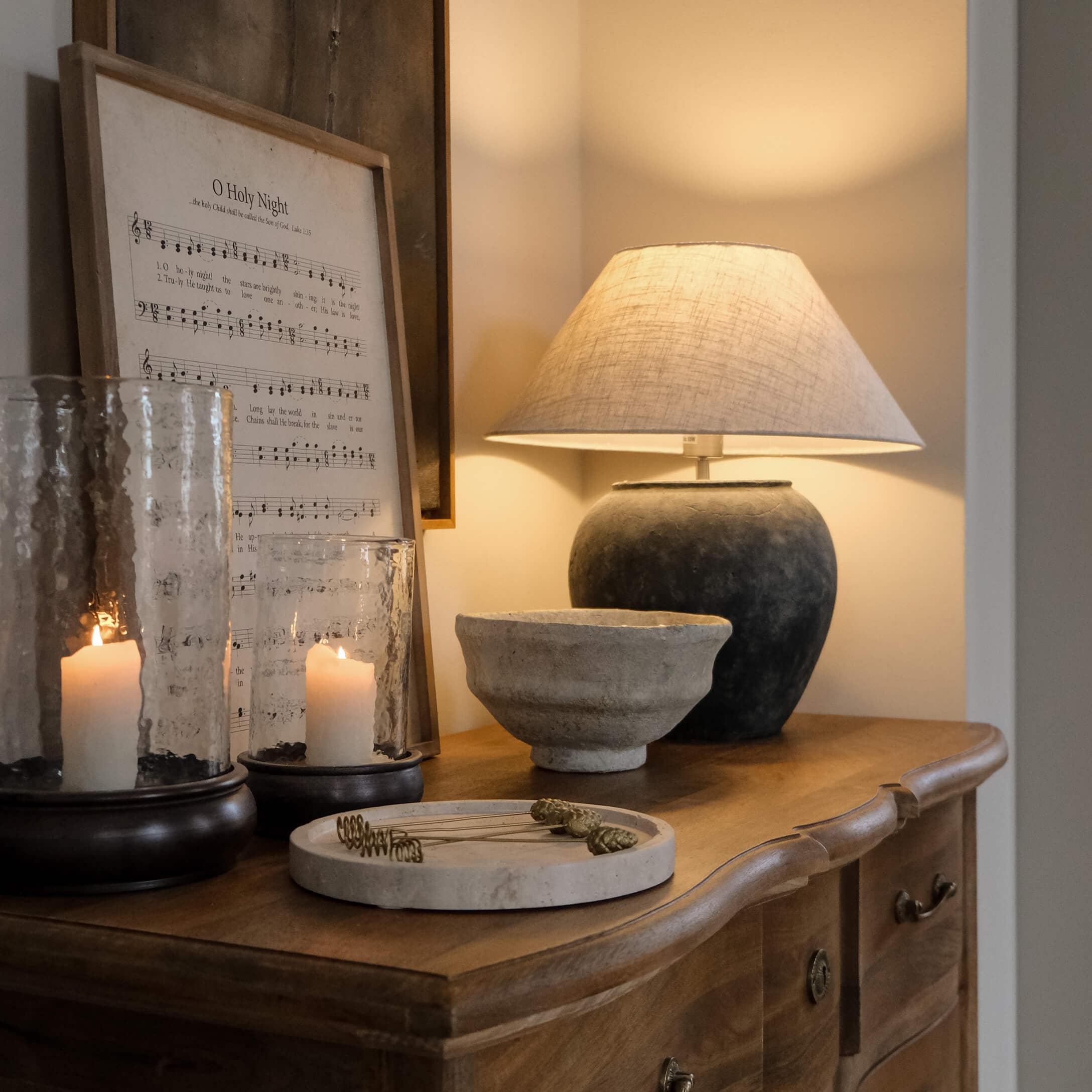 Lampe de table avec base en céramique noire et abat-jour beige sur commode en bois avec décorations