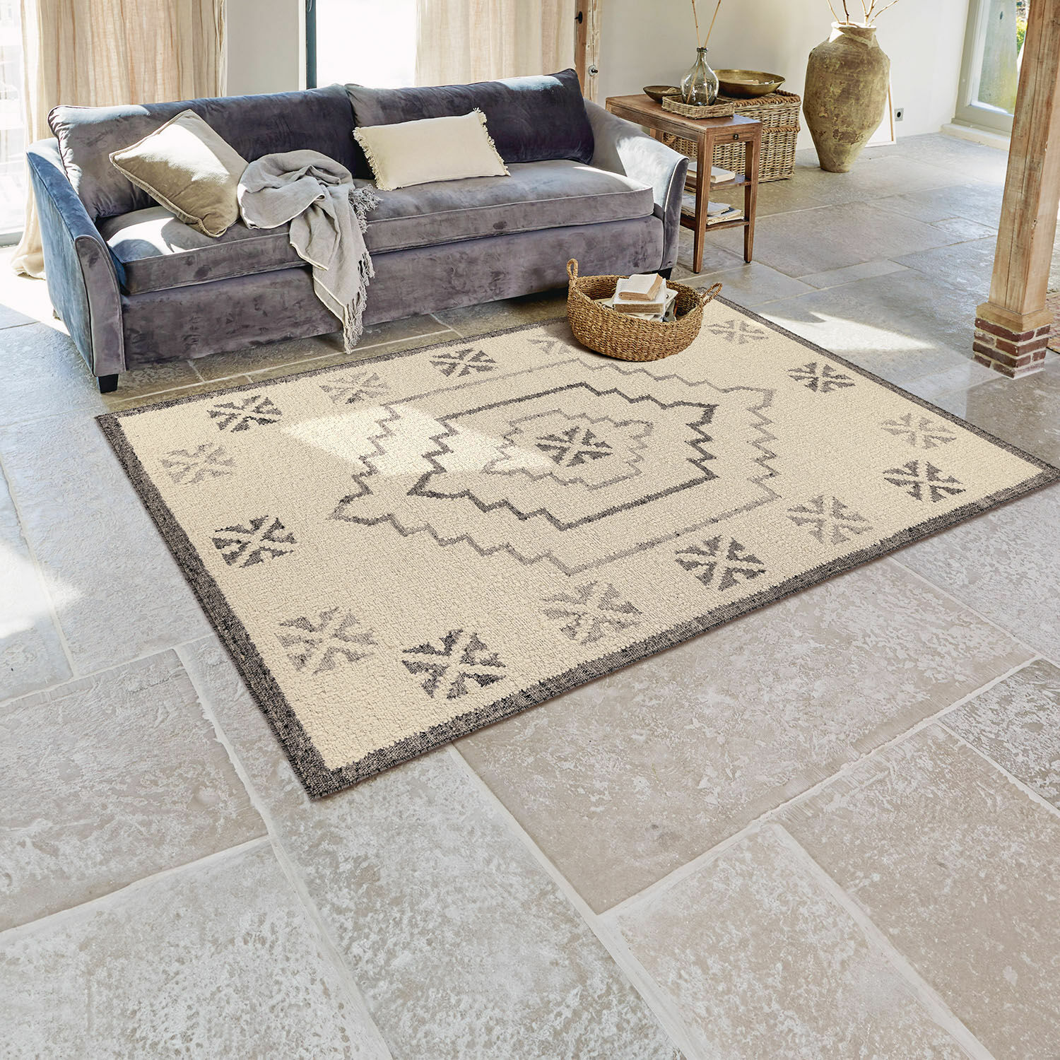 Vloerkleed Xerven Beige vloerkleed met grijs geometrisch patroon op stenen vloer in lichte woonkamer