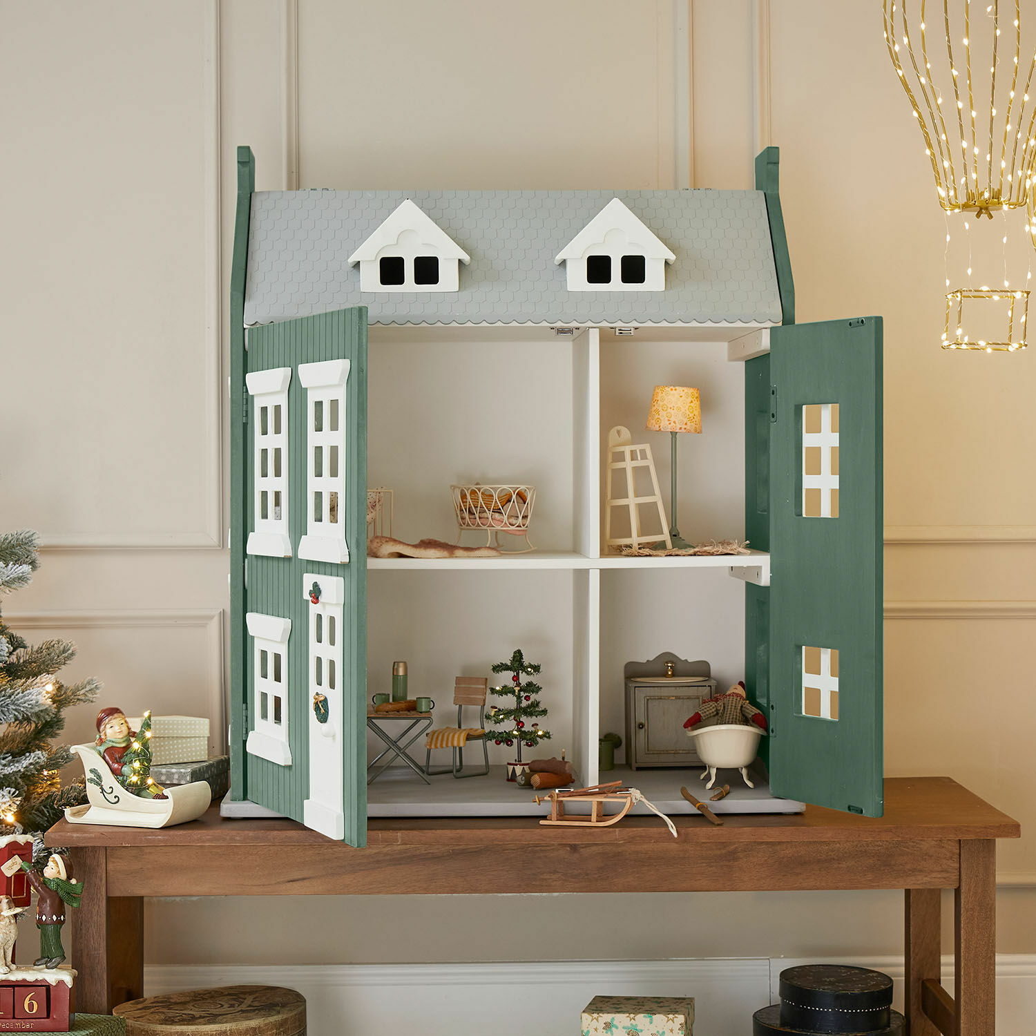 Maison de poupées Avenari Maison de poupée en bois vert et blanc avec meubles et décorations de Noël sur une table en bois