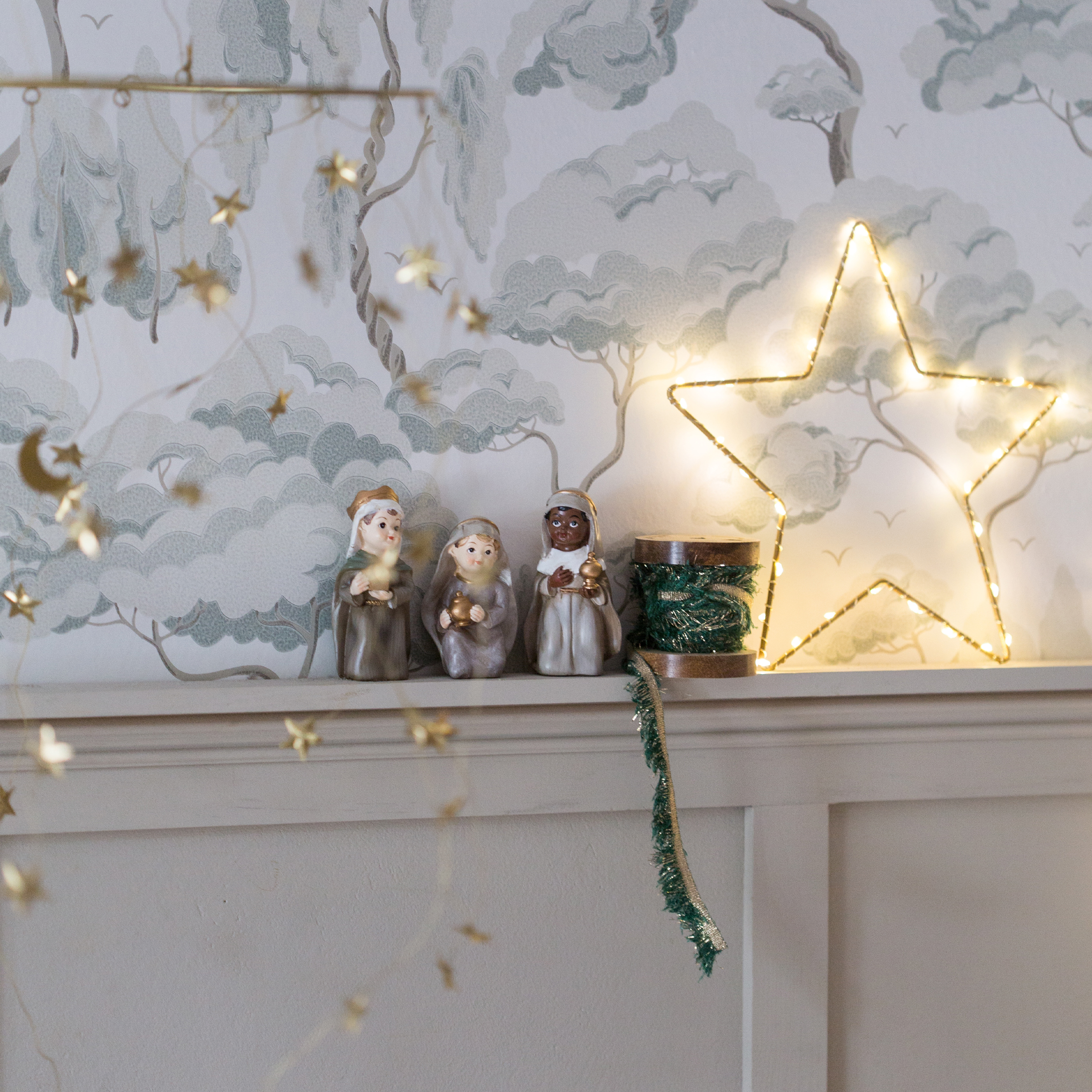 Décoration de Noël avec trois figurines des Rois Mages et une étoile lumineuse sur une étagère blanche