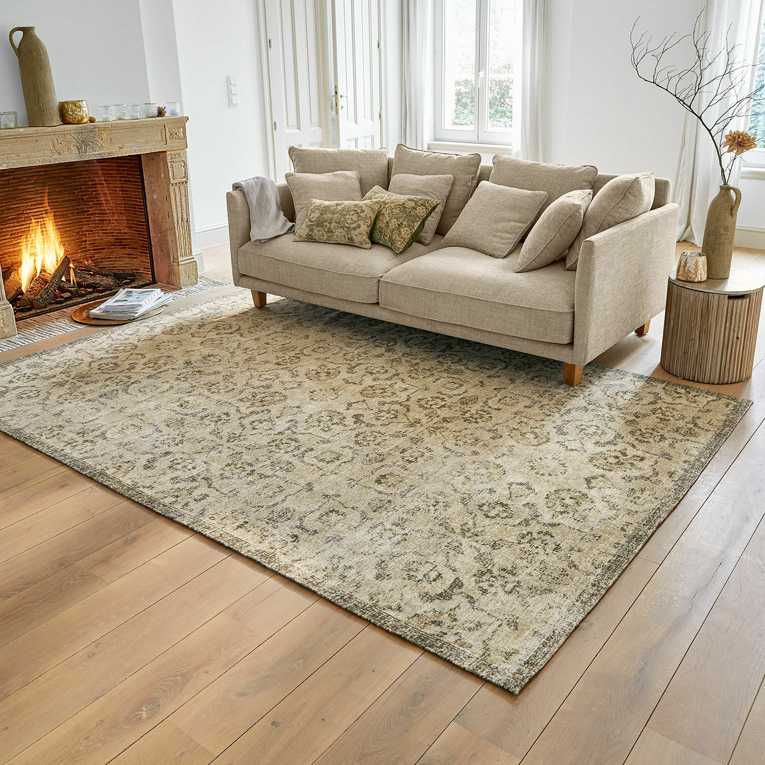 Tapis Calperino Tapis beige à motif subtil sur parquet en bois dans un salon avec canapé beige et cheminée