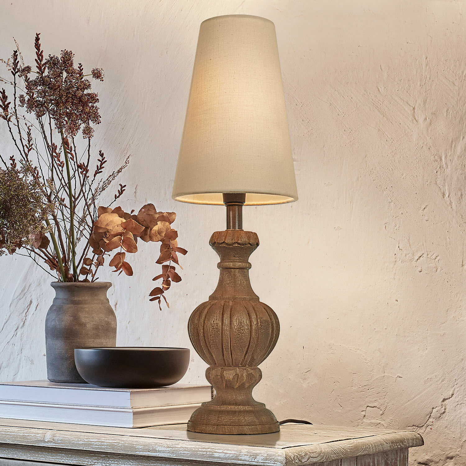 Lampe à poser Airoux Lampe de table avec base en bois sculpté et abat-jour crème sur une table rustique décorée