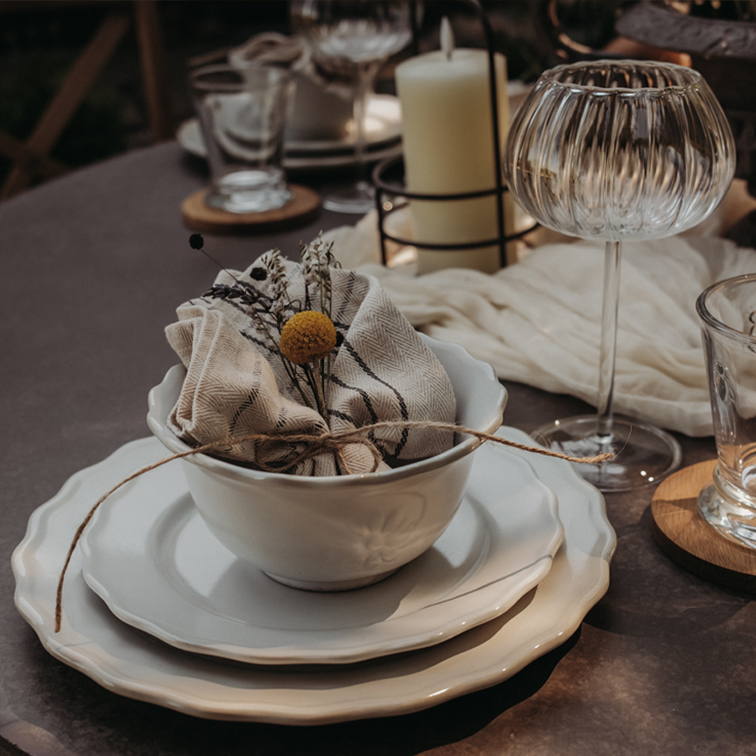 Set witte keramiek met kom, borden en linnen servet met bloemdecoratie op tafel