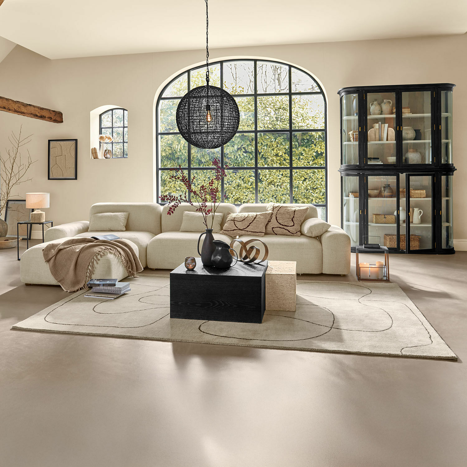 Vloerkleed Lavinois Ruime woonkamer met beige stoffen bank en zwarte houten salontafel op patroon vloerkleed