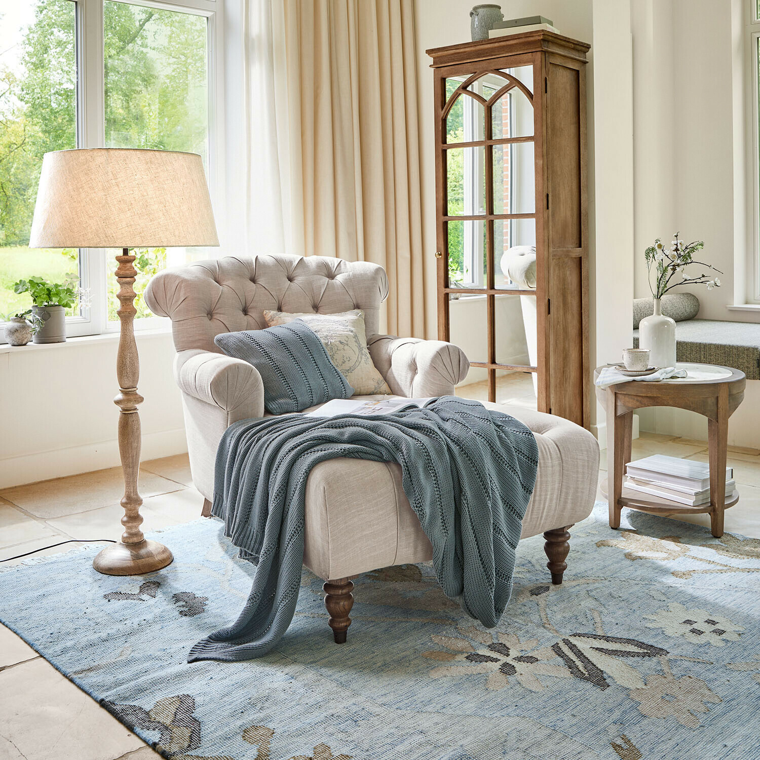 Chaise longue Springfield Village Beige stoffen fauteuil met gestikte rugleuning en blauwe deken op blauwe vloerkleed in lichte woonkamer
