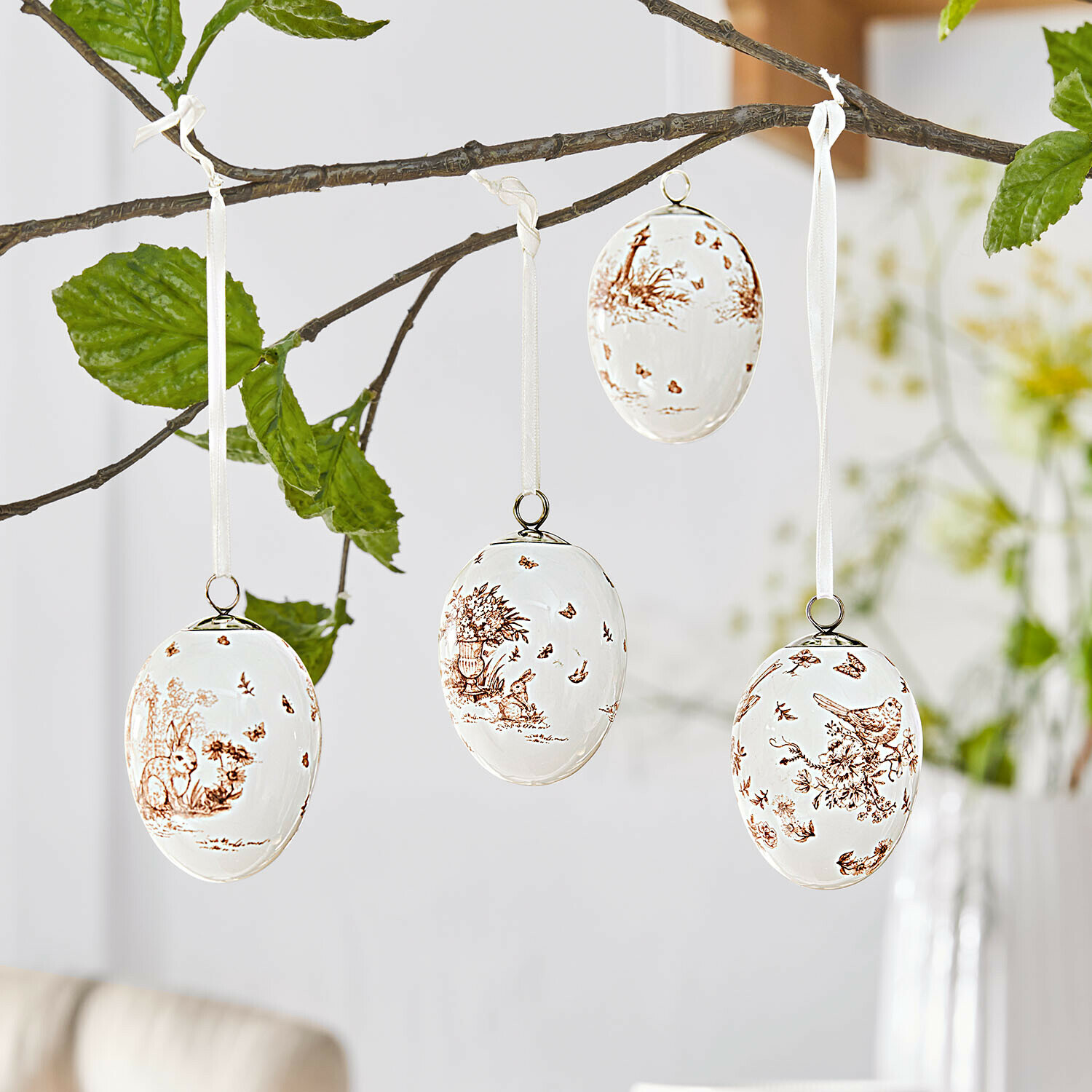 Hanger set van 4 Seravoux Witte keramische paaseieren met bruine dieren- en plantenmotieven, hangend aan een tak