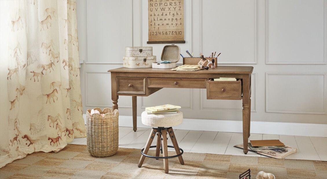 Bureau en bois avec trois tiroirs et tabouret rembourré clair dans une pièce d'étude chaleureuse