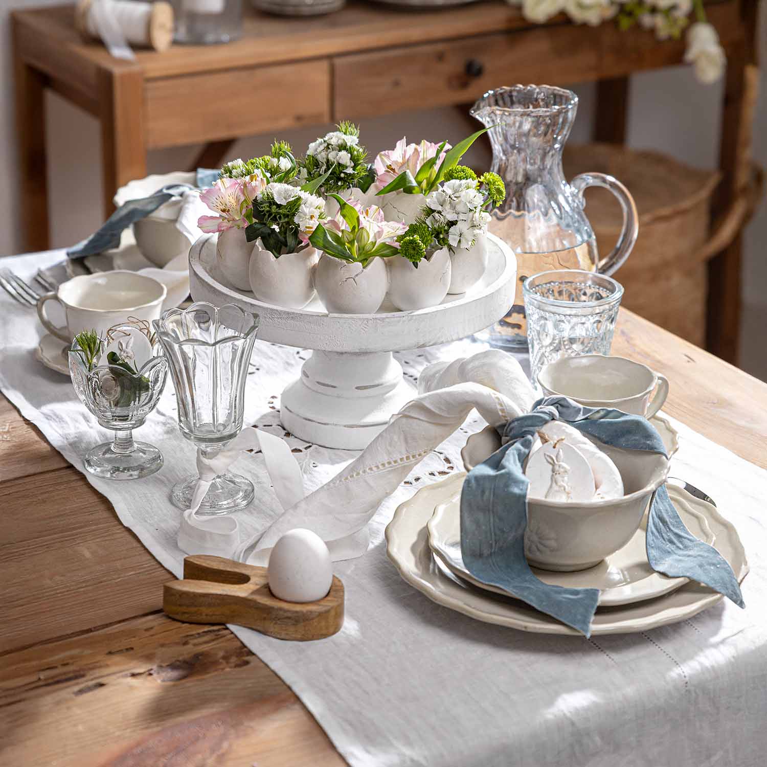 Présentoir en céramique blanche avec pots en forme d'œufs et fleurs, décor de table en bois rustique
