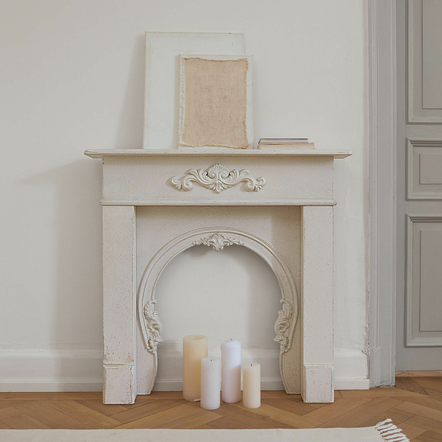 Haardschouw Jarnéville Witte decoratieve schoorsteenmantel met ornamenten en kaarsen op houten vloer in vintage stijl